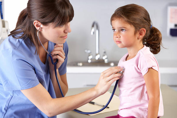 A nurse checking a little kid's heart beat